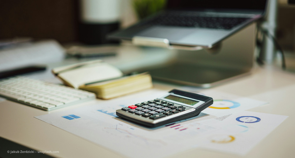 Unterlagen und Taschenrechner liegen auf dem Schreibtisch © Jakub Żerdzicki – unsplash.com